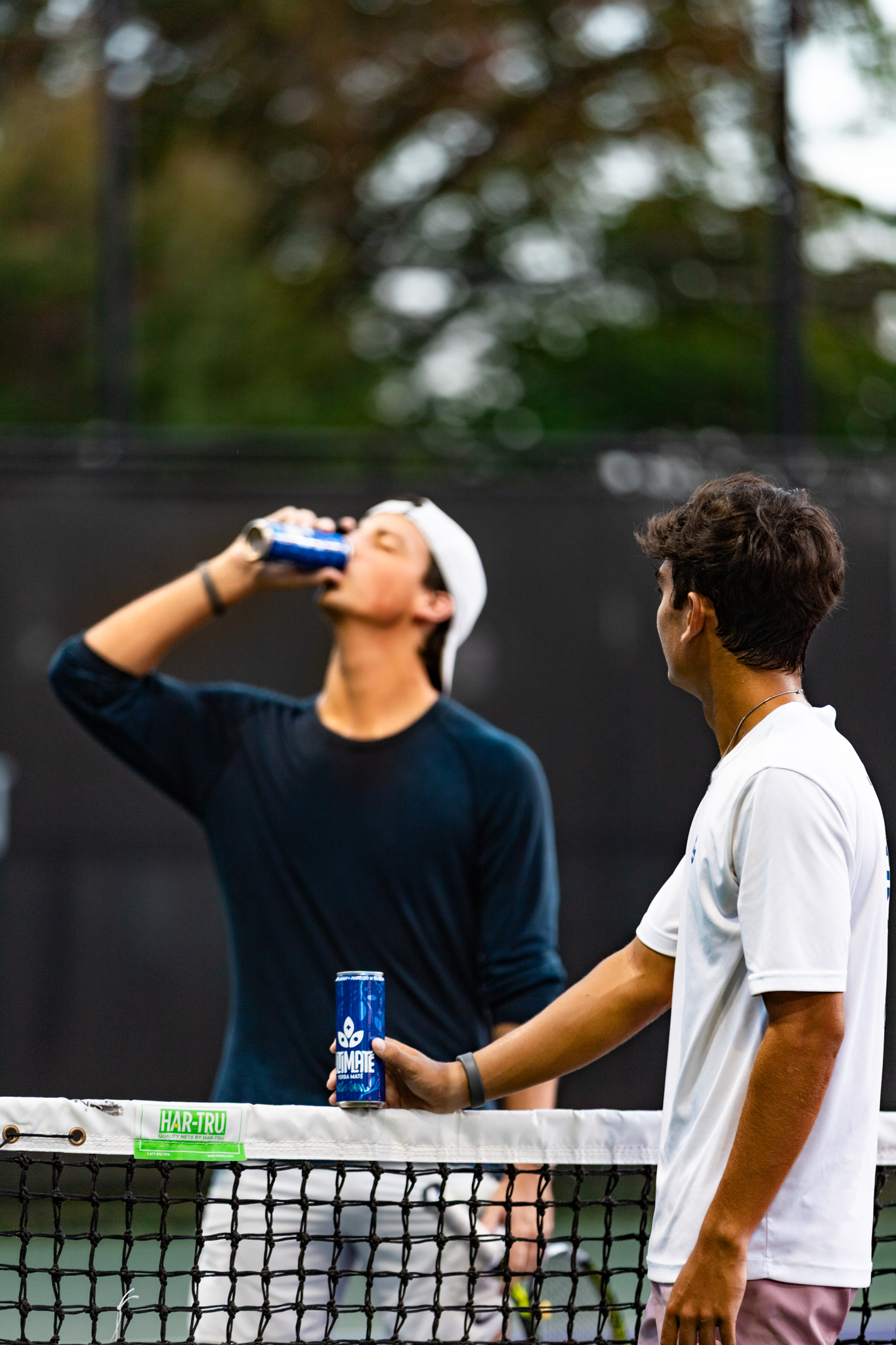 Tennis players sharing an Ultimate can at the net